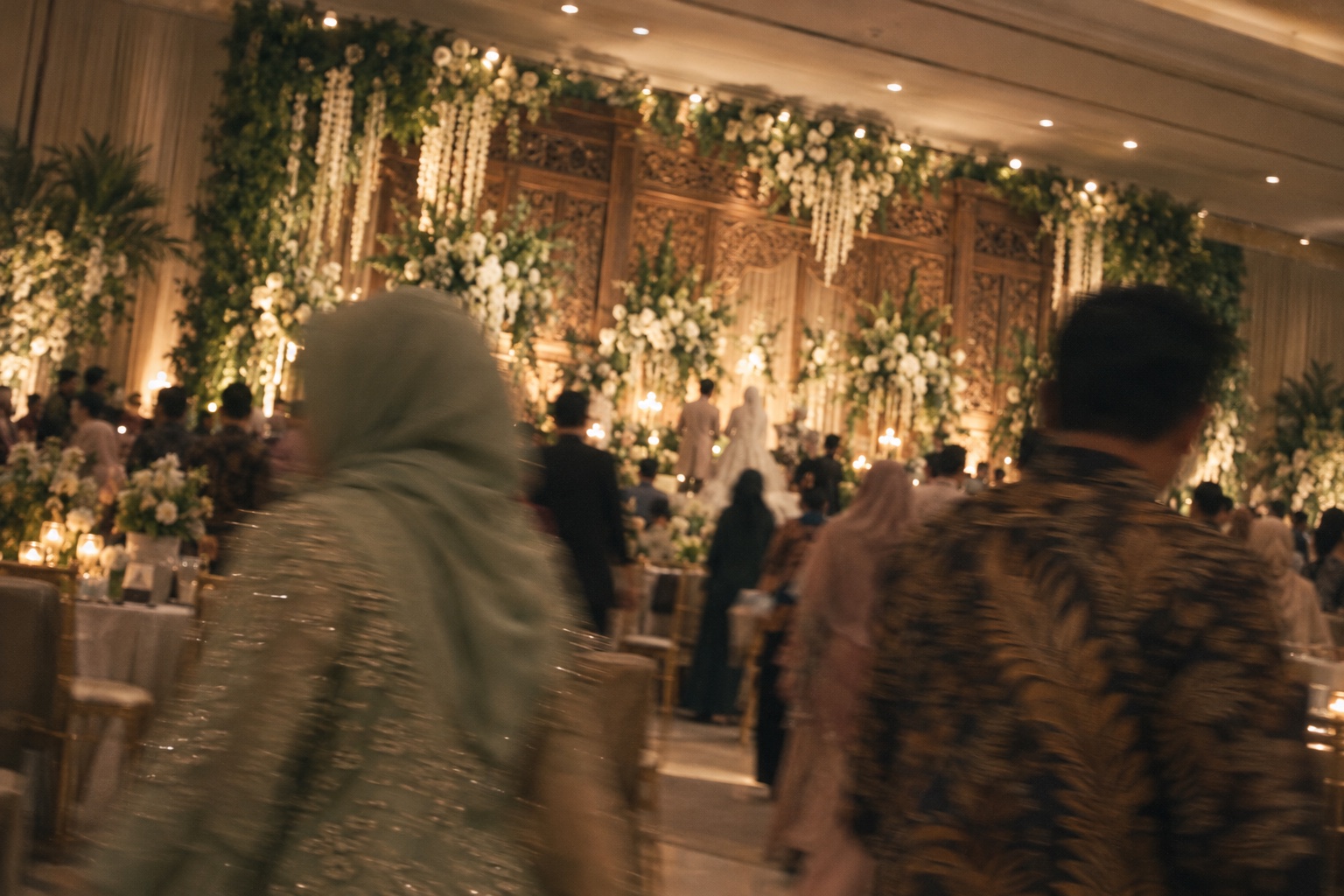 Ilustrasi AI: Tamu berbatik dan berhijab di resepsi gedung dengan efek gerakan buram